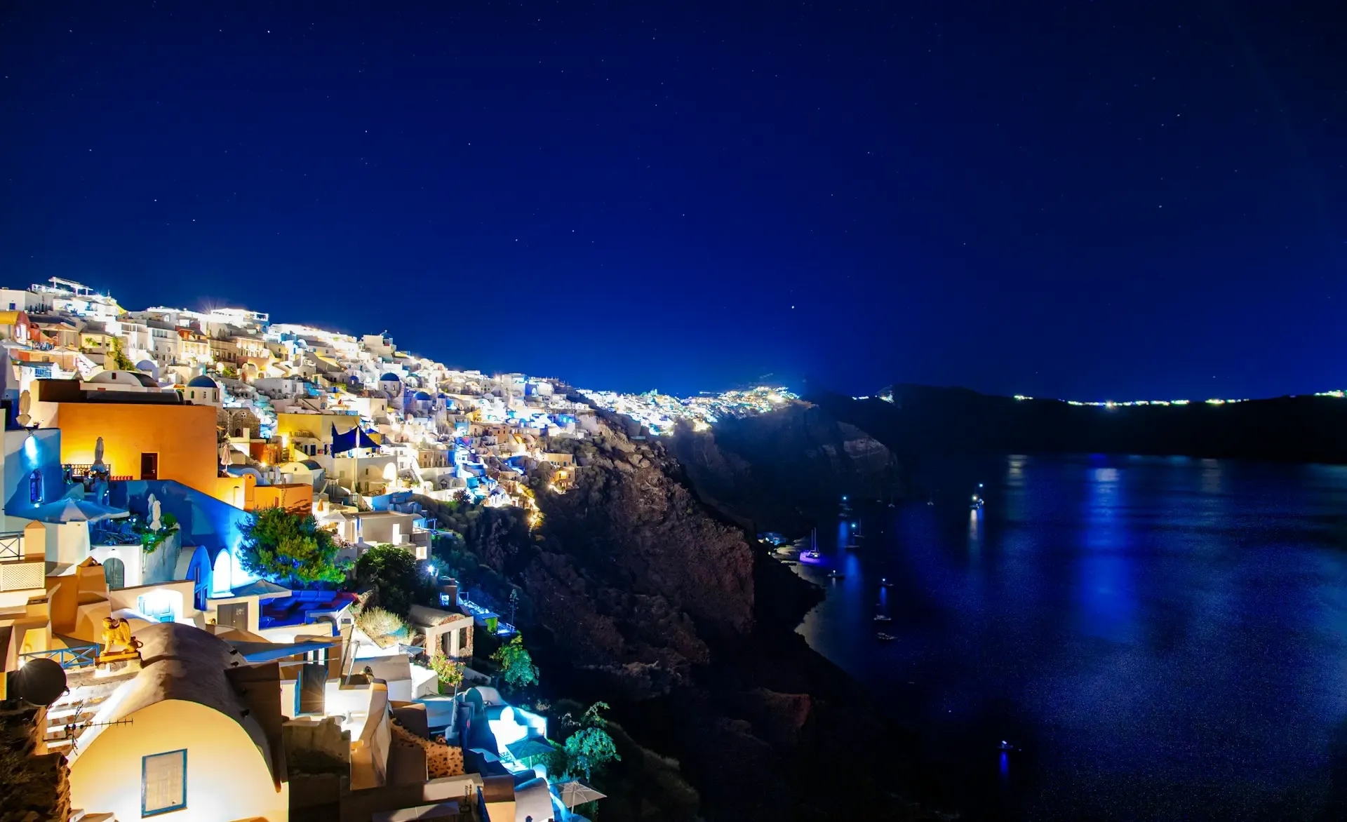 Pueblo de Oia en Santorini iluminado de noche sobre los acantilados frente al mar Egeo