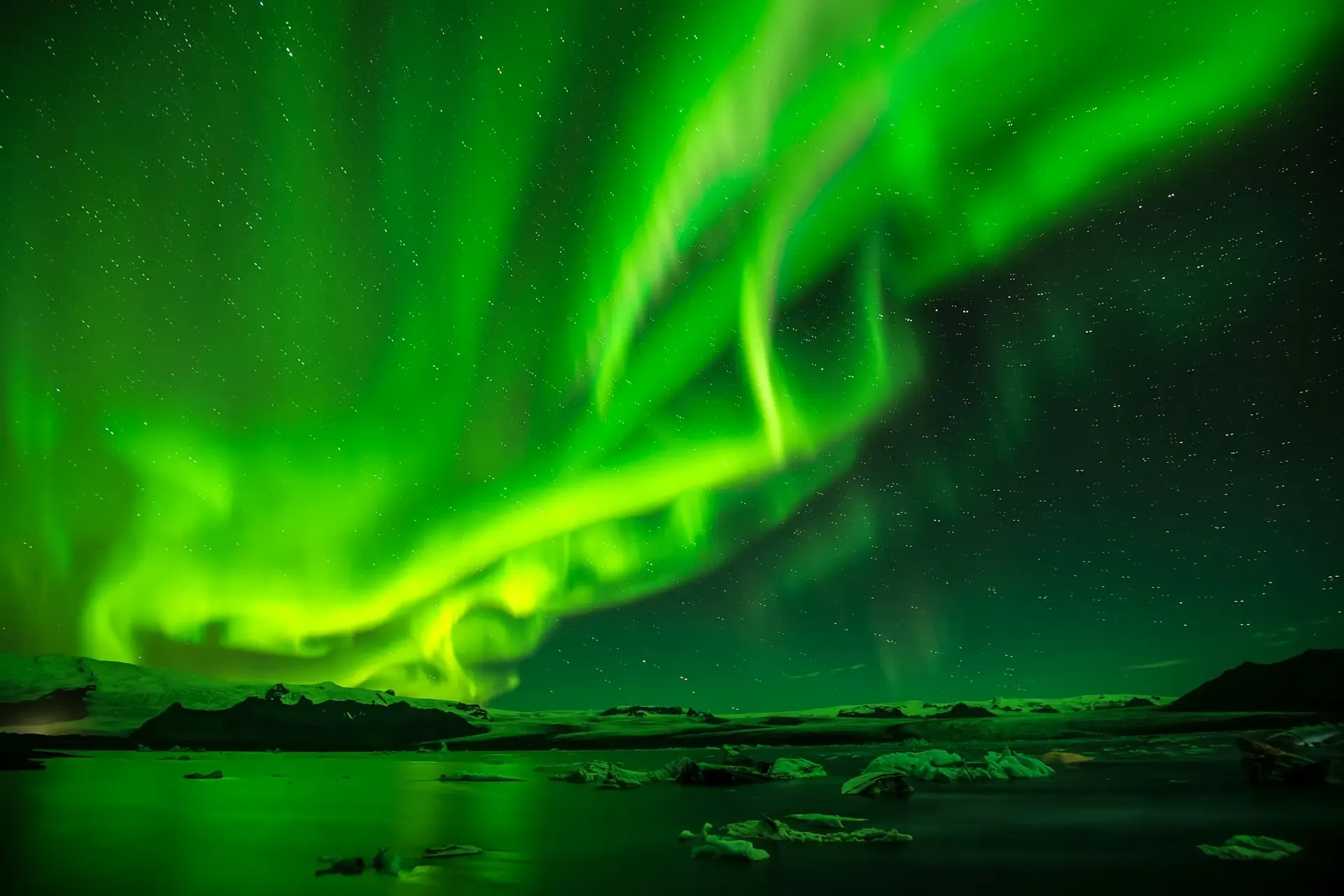 Aurora boreal verde ondulando sobre un paisaje helado bajo un cielo estrellado