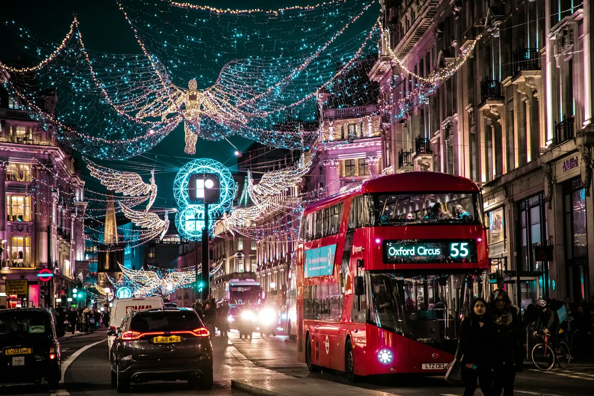 Calle de Londres decorada con luces navideñas en forma de ángel, con un autobús rojo de dos pisos
