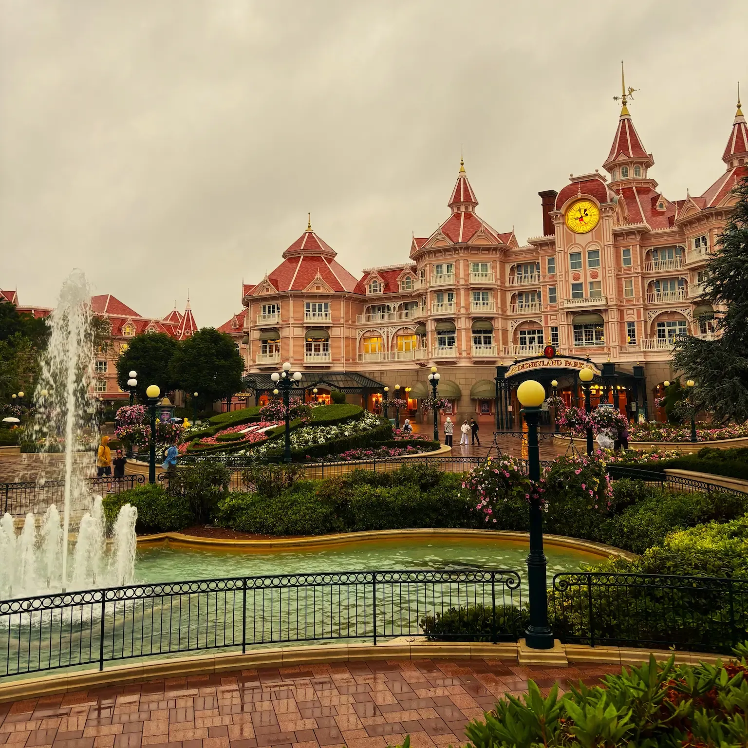 Entrada de Disneyland Paris en un día de lluvia, con el Disneyland Hotel y la fuente de la plaza