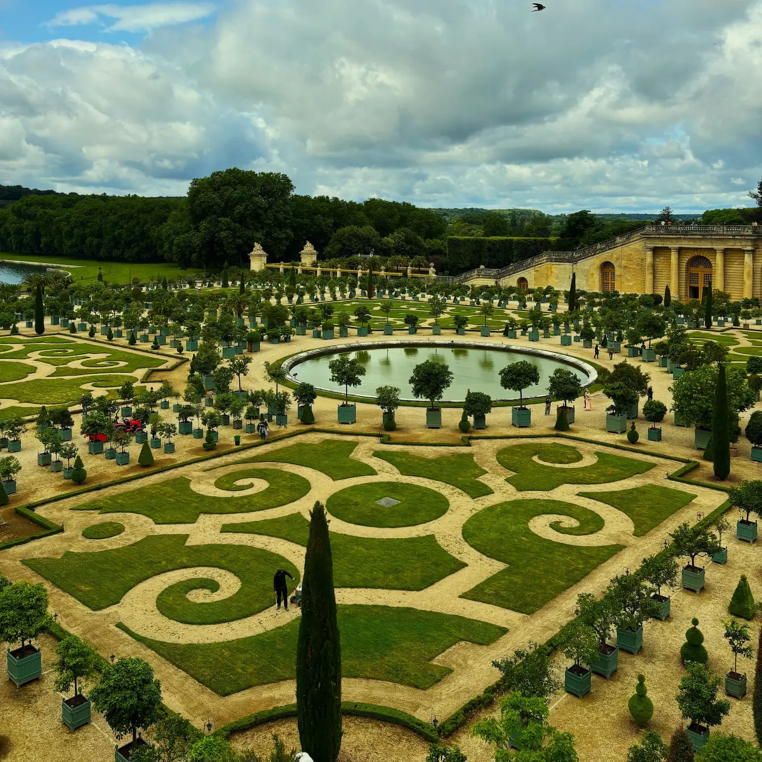 Parterre de la Orangerie de Versalles, con los naranjos en maceta alrededor del estanque circular