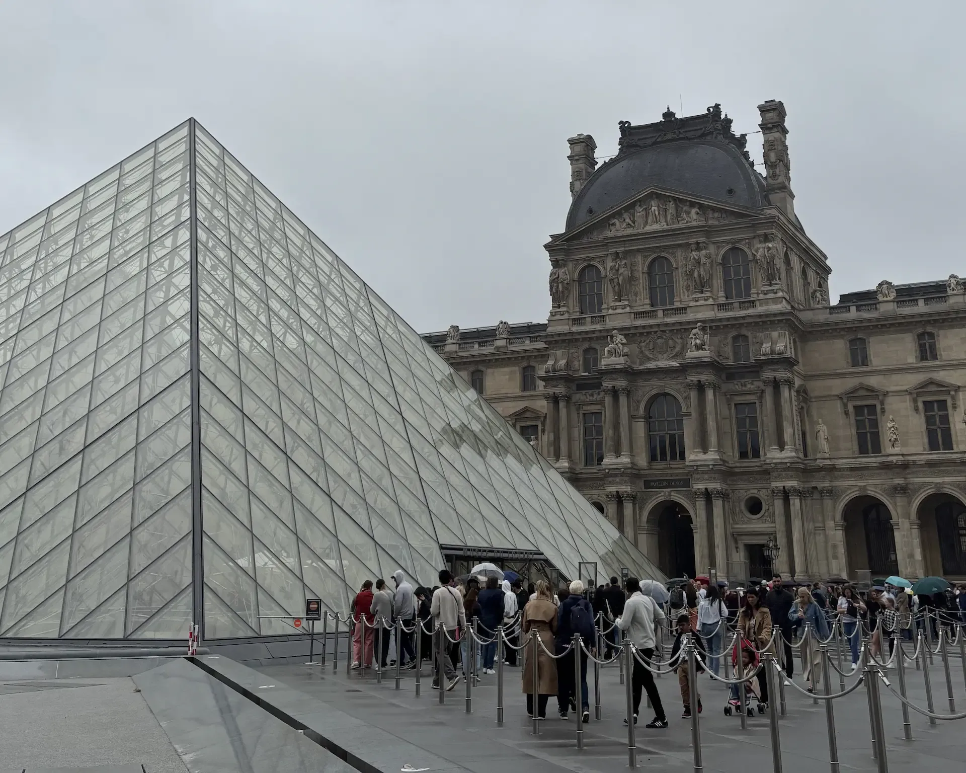Cola de entrada bajo la pirámide de cristal del Louvre, con el Pabellón Denon al fondo